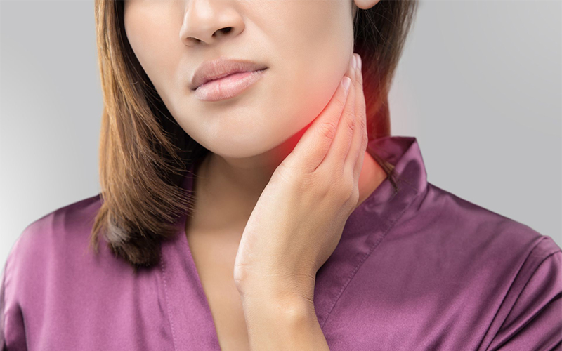 Woman with a sore throat holding her neck